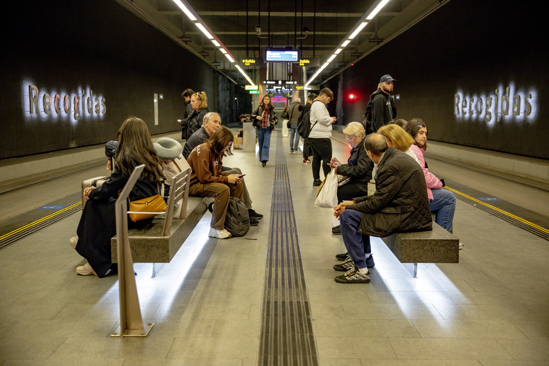 usuarios del Metropolitano de Granada sentados en el andén de la Estación de Recogidas